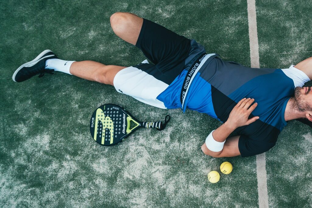 男性がテニスコートで寝ている